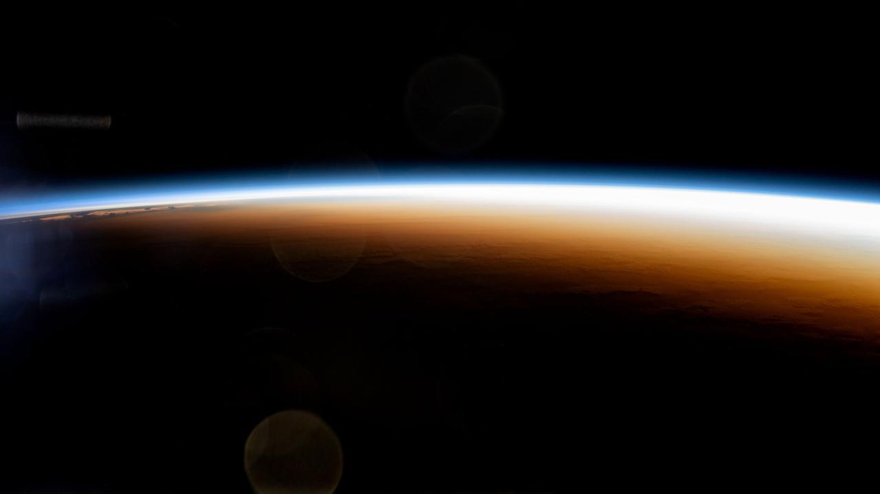 An orbital sunrise illuminates the Earth's atmosphere, seen from the ISS